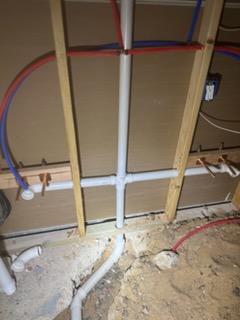 New construction rough-in with PEX supply lines and PVC drain tee in an open wall