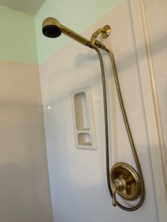 Brushed brass handheld shower fixture installed in a remodeled shower