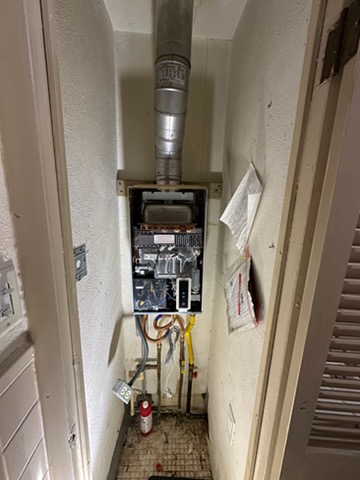 Tankless water heater installed in a utility closet with venting